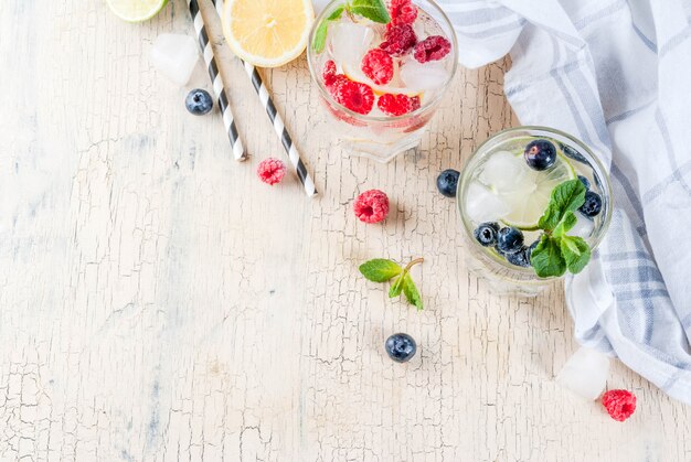 Verschillende bessenlimonade of mojito-cocktails, vers ijscitroen limoen frambozen bosbessen doordrenkt water