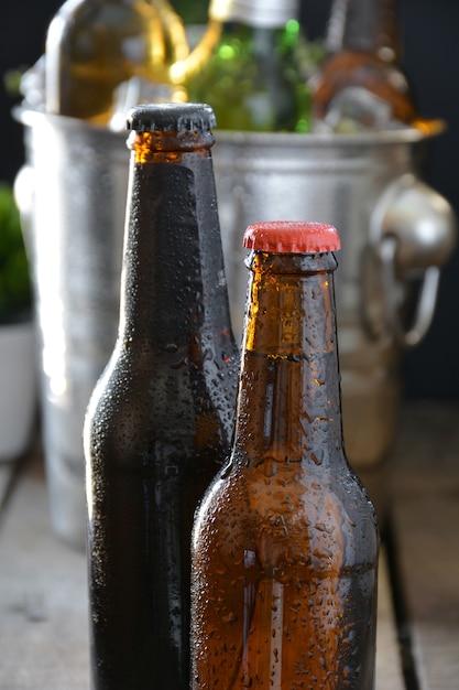 Verschillende bieren op een tafel van hout. er zijn fles en glas met ijs om ze koud te houden