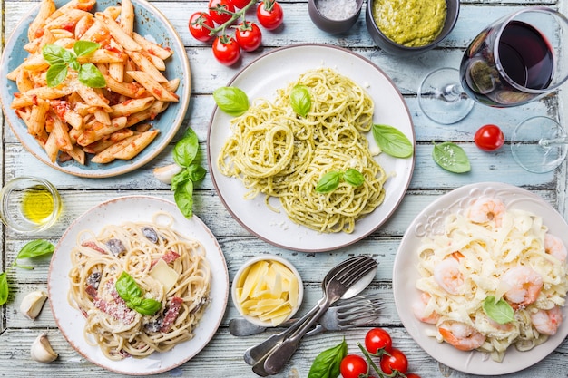 Verschillende borden pasta met verschillende soorten saus over houten