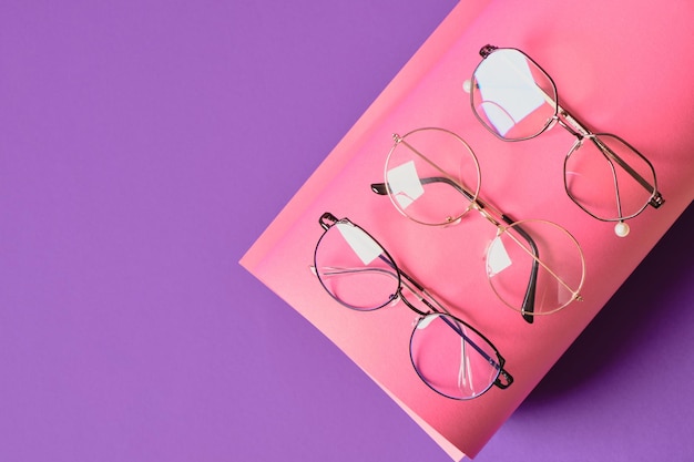 Verschillende brillen op roze en paarse geometrische achtergrond, trendy brilmonturen kopiëren ruimte