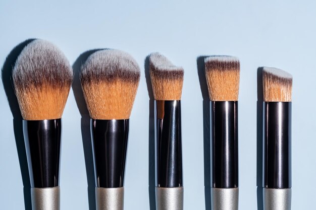 Verschillende cosmetische borstels op een blauwe achtergrond Make-up borstel set voor huidverzorging Professionele make-up concealer Poeder Blush oogschaduw