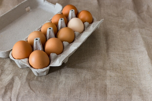 Verschillende eieren in een kartonnen doos op grijs
