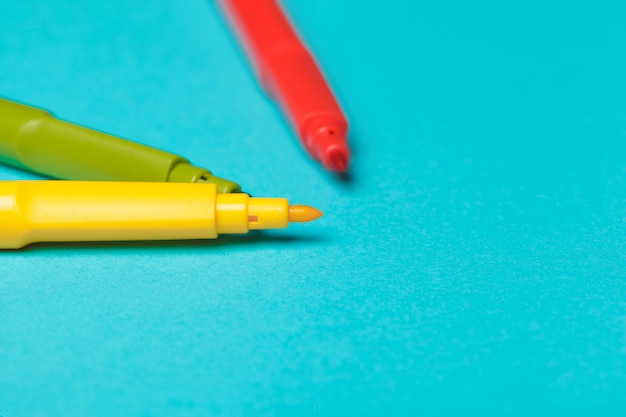 Verschillende gekleurde viltstiften op helder blauw papier close-up