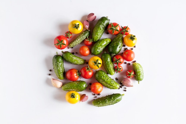 Verschillende groenten in de vorm van rode en gele tomaten, komkommers, knoflook en zwarte pepererwten zijn aangelegd
