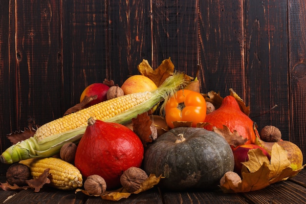 Verschillende groenten, pompoenen, appels, peren, noten, tomaten, maïs, droge gele bladeren op houten achtergrond. herfststemming, copyspace. oogst.