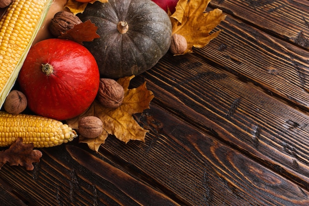 Verschillende groenten, pompoenen, appels, peren, noten, tomaten, maïs, droge gele bladeren op houten achtergrond. herfststemming, copyspace. oogst.