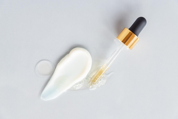 Foto verschillende huidverzorging product textuur stalen op grijze achtergrond essence olie of serum en gezichtscrème pipet druppelaar cosmetische uitstrijkjes