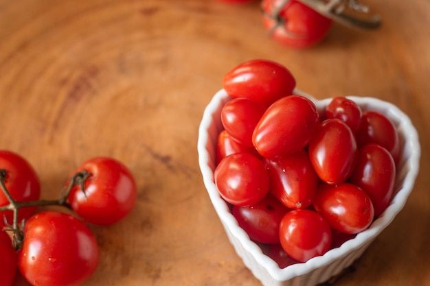 Verschillende kleine tomaten in witte kom op een houten tafel