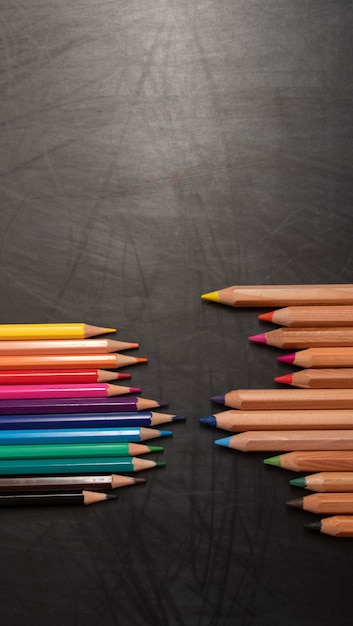 Verschillende kleuren houten potloden op zwarte bordachtergrond