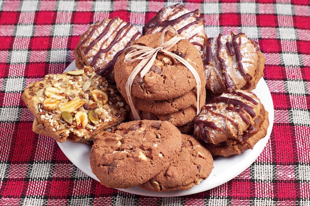 Verschillende koekjes in witte plaat op rustieke tafel met rood tafelkleed