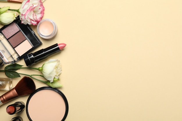 Verschillende make-up cosmetica en bloemen op beige achtergrond