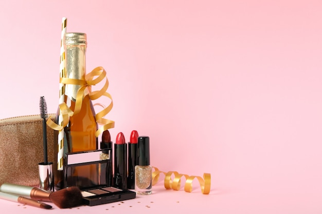Verschillende make-up cosmetica en champagne op roze achtergrond