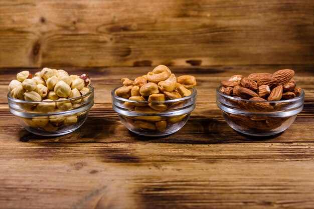 Verschillende noten amandel cashew hazelnoot in glazen kommen op een houten tafel Vegetarische maaltijd Gezond eten concept