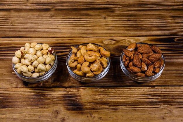 Verschillende noten amandel cashew hazelnoot in glazen kommen op een houten tafel Vegetarische maaltijd Gezond eten concept