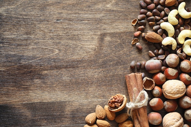 Verschillende noten op een houten tafel. Ceder, cashew, hazelnoot, walnoten en een lepel op tafel. Veel noten zijn in de schaal en chistchenyh op een houten achtergrond