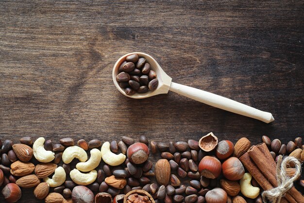 Verschillende noten op een houten tafel. Ceder, cashew, hazelnoot, walnoten en een lepel op tafel. Veel noten zijn in de schaal en chistchenyh op een houten achtergrond