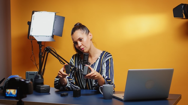 Verschillende np-f-stijlbatterijen op het vloggerbureau, die ze naar de camera brengen. contentmaker nieuwe media-sterbeïnvloeder op sociale media die professionele videofotoapparatuur voor online internet spreekt