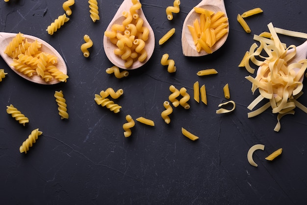 Verschillende pasta op lepels op stenen achtergrond