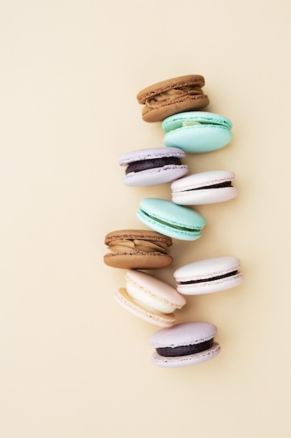 Verschillende pastelkleuren gebak macarons bovenaanzicht op een beige achtergrond