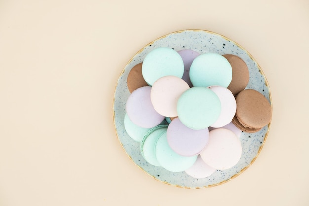 Verschillende pastelkleuren gebak macarons bovenaanzicht op een beige achtergrond