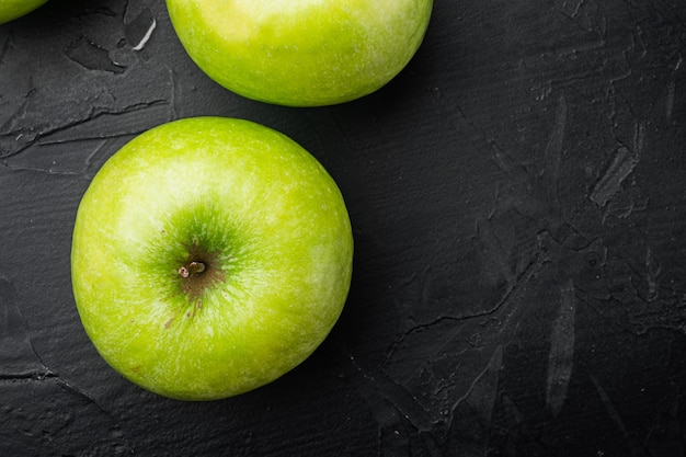 Verschillende rijpe groene appels, op zwarte donkere stenen tafelachtergrond, bovenaanzicht plat gelegd, met kopieerruimte voor tekst