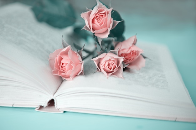 Verschillende roze rozen op een open boek op een groene tafel
