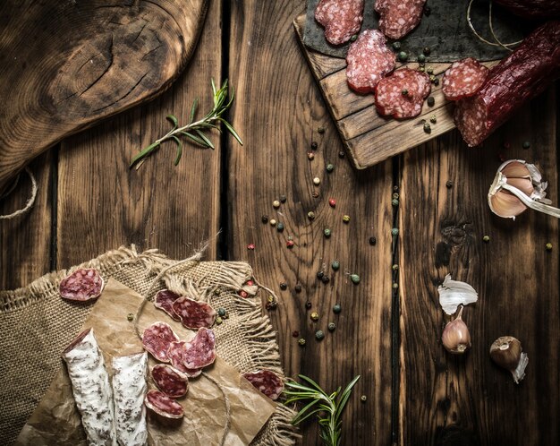 Verschillende salami met kruiden en specerijen. Op houten tafel.