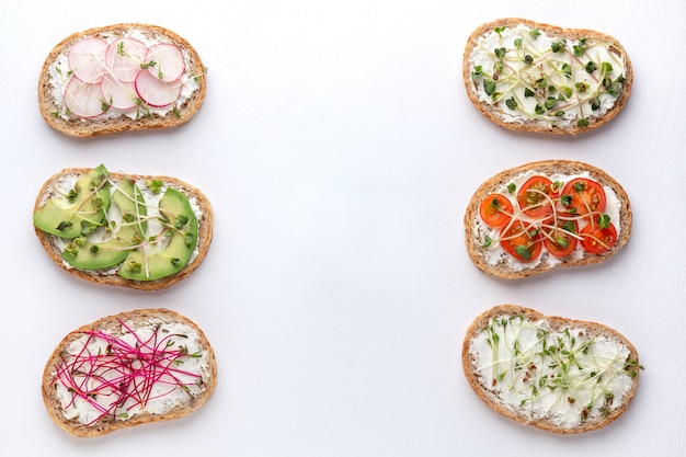 Verschillende sandwiches met graan brood, groenten en microgreens op een witte achtergrond