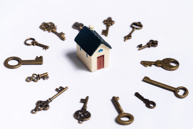 Verschillende sleutels en een huisje op een witte achtergrond, concept van onroerend goed