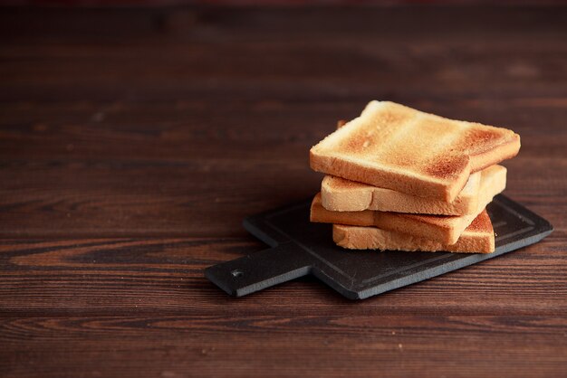 Verschillende sneetjes geroosterd brood toast op een houten donkere achtergrond.