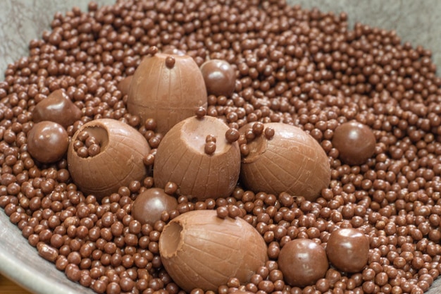 Verschillende soorten chocoladeballen in een grijze kom op een houten tafel