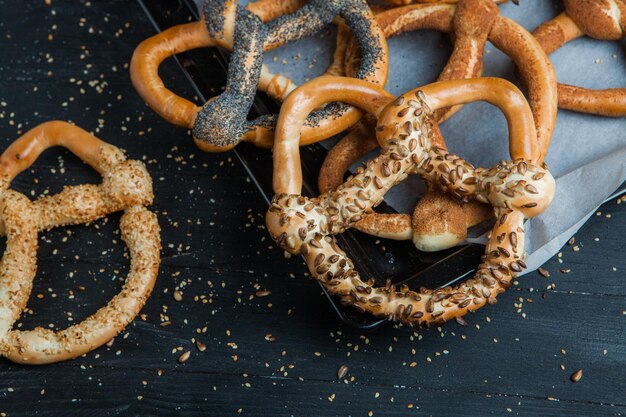 Foto verschillende soorten gebakken pretzels of bagels met zaden op een zwarte achtergrond