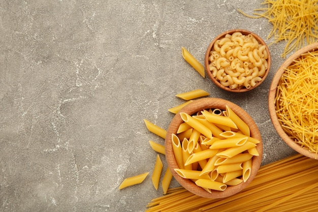 Verschillende soorten italiaanse pasta op grijze achtergrond