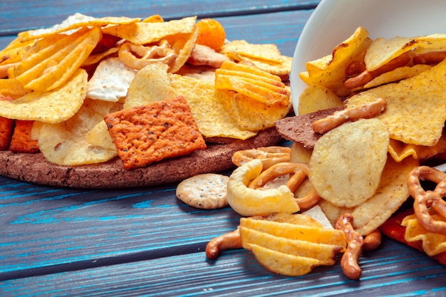 Foto verschillende soorten junkfood, zoute stokjes, zoute crackers op houten tafel in het stilleven