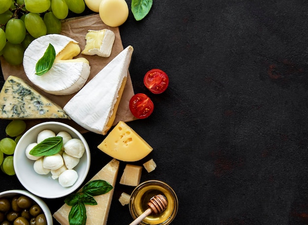 Foto verschillende soorten kaas, druiven, honing en snacks op een zwarte betonnen achtergrond