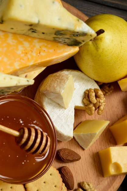 Verschillende soorten kaas op een rustieke houten tafel Assortiment kazen met noten, fruit en honing