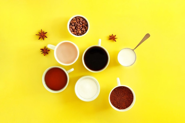 Verschillende soorten keramische witte kopjes koffie thee suiker crème en steranijs op een gele achtergrond
