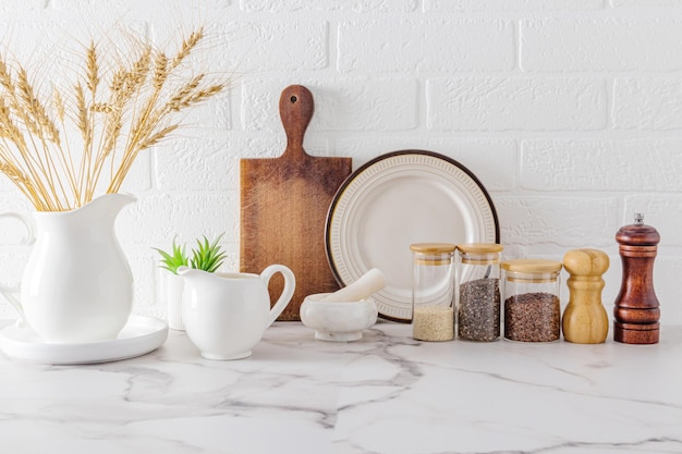 Verschillende soorten keukengerei en gebruiksvoorwerpen op een marmeren aanrechtblad tegen een witte bakstenen muur vooraanzicht ecologisch schone keuken