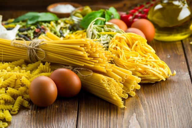 Verschillende soorten pasta op tafel met basilicum en olijven, ook met kippeneieren