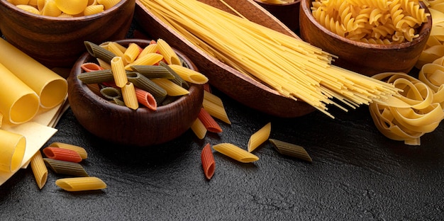 Verschillende soorten pasta op zwarte achtergrond met kopie ruimte voor tekst