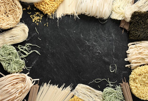 Verschillende soorten rauwe Aziatische noedels Soba Ramen Ramyeon Misua Char Kway Teow Vegetable Egg Noodle Somen Op zwart marmer Tafel met kopieerruimte in het midden