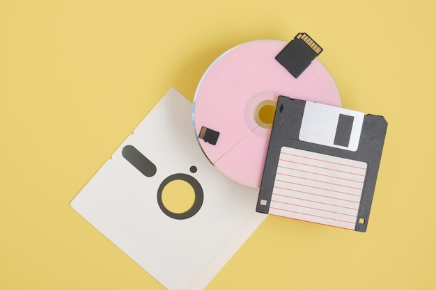 Verschillende soorten schijven voor het opslaan van informatie op een gele achtergrond, moderne en retro schijven en diskettes bovenaanzicht