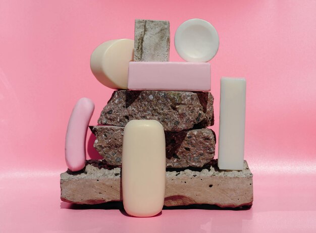 Foto verschillende soorten stukken zeep trendy stijl organische stukken zeep op een roze achtergrond stenen voetstuk witte en roze zeep in verschillende vormen reinigings- en spa-concept geometrische vormen opgezet