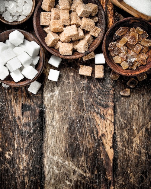 Verschillende soorten suiker in kommen op een houten achtergrond