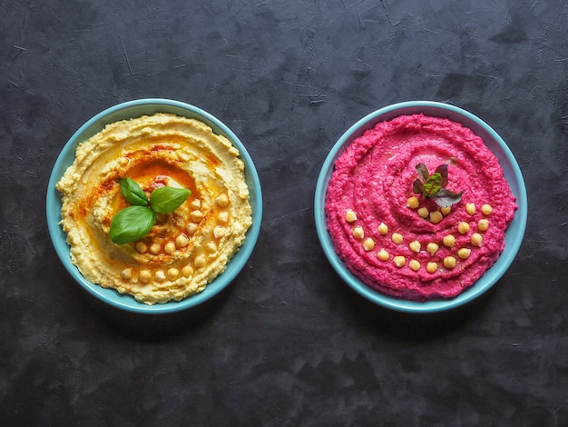 Verschillende soorten traditionele hummus op de zwarte tafel. Hummus met rode biet op een zwarte keukentafel.