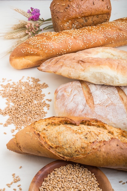 Verschillende soorten vers gebakken brood op een witte houten oppervlak. zijaanzicht.