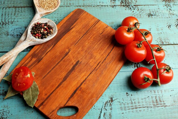 Verschillende specerijen en kruiden met snijplank op een kleurrijke houten tafel achtergrond
