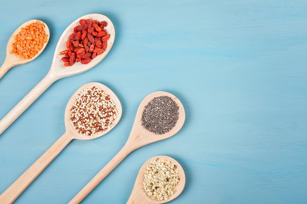 Verschillende superfoods goji bessen, quinoa, chia, hennepzaden en lantils op blauwe achtergrond. veganistisch, vegetarisch en gezond eetdieet en biologisch productenconcept