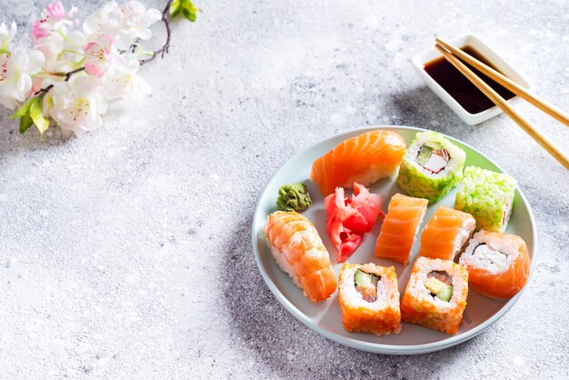 Verschillende sushi op plaat met stokken op lichte steenachtergrond