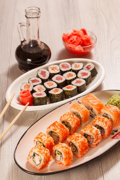 Verschillende sushi rolt met rijst groente zeevruchten op keramische platen glazen fles met sojasaus